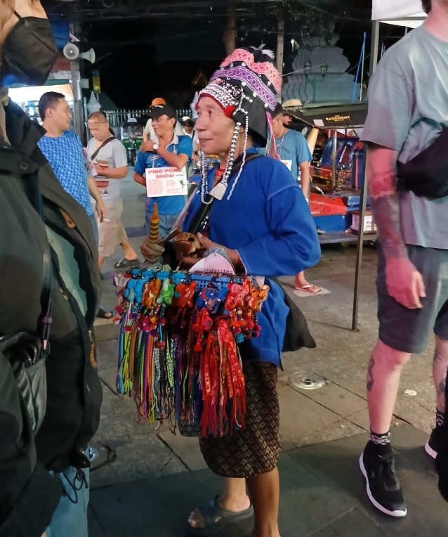An elderly woman street peddler wearing traditional attire.