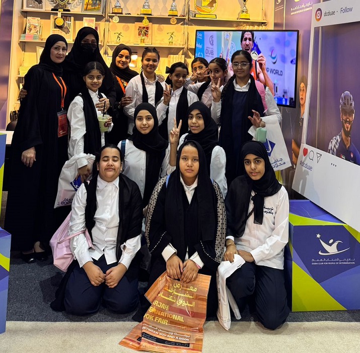 Members of Dubai Club for People of Determination posing in front of their booth at the SIBF 2025. 