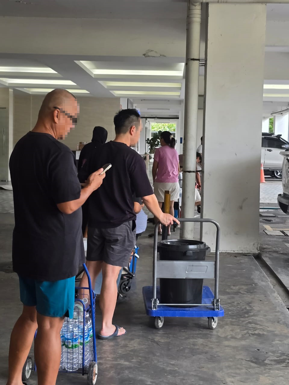 Some of the 350-plus occupants lining up to get water from the hose near the main entrance to the condominiums.