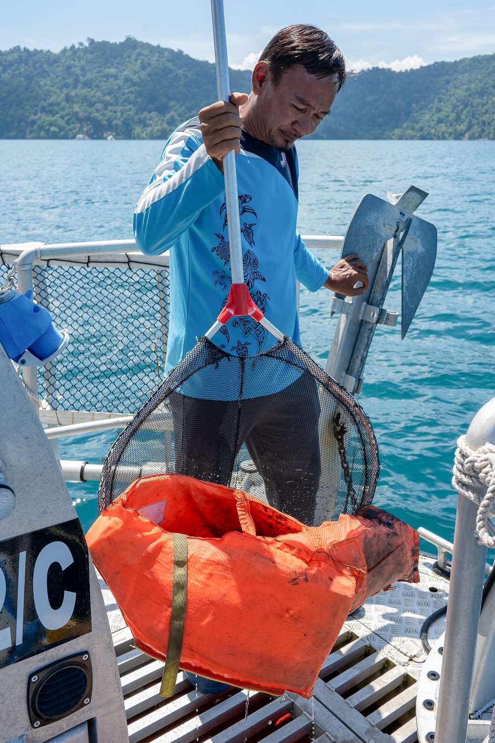 A crew member retrieving a discarded life jacket from the sea. Objects like this, often lost or thrown overboard, are frequently found trapped among the reefs or floating on the surface.
