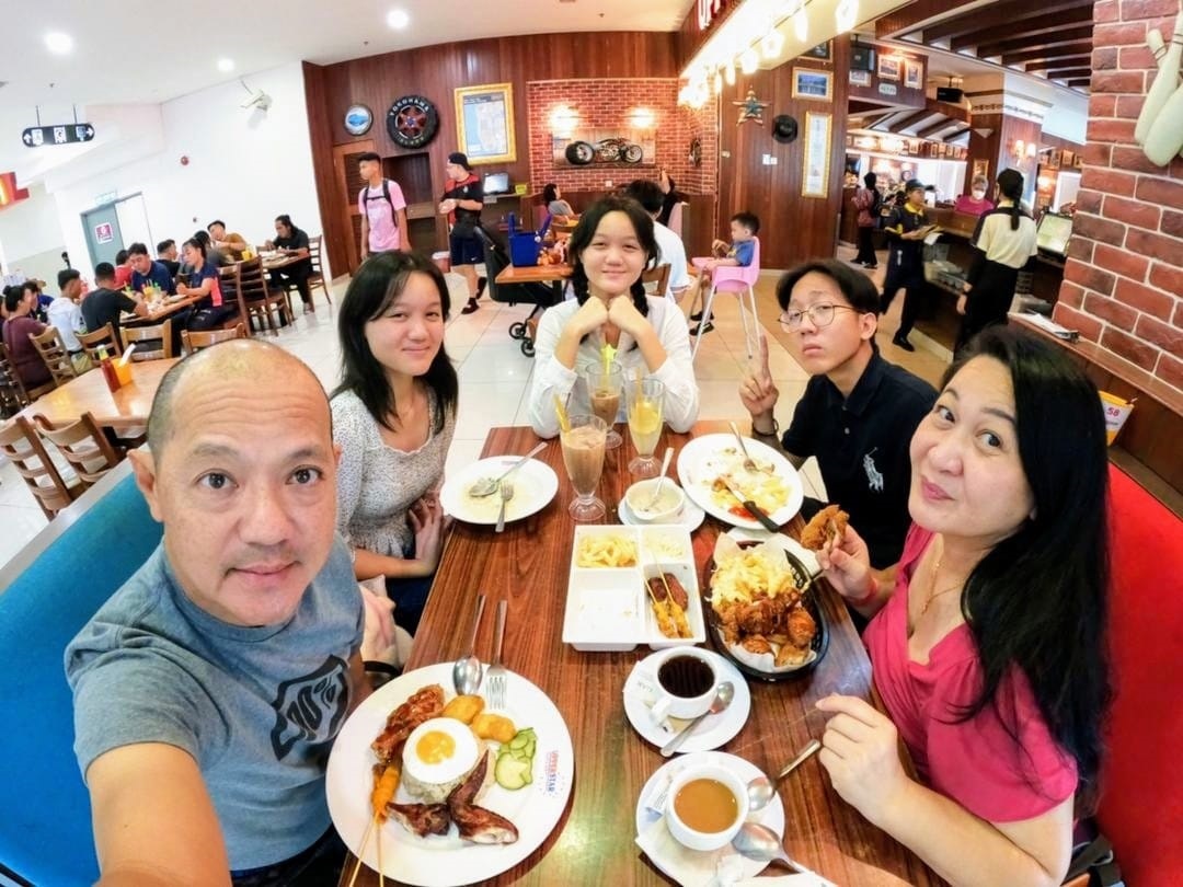 Marjorie and her husband enjoying a family meal with their children at a shopping mall in Kota Kinabalu. (Pic: Provided)