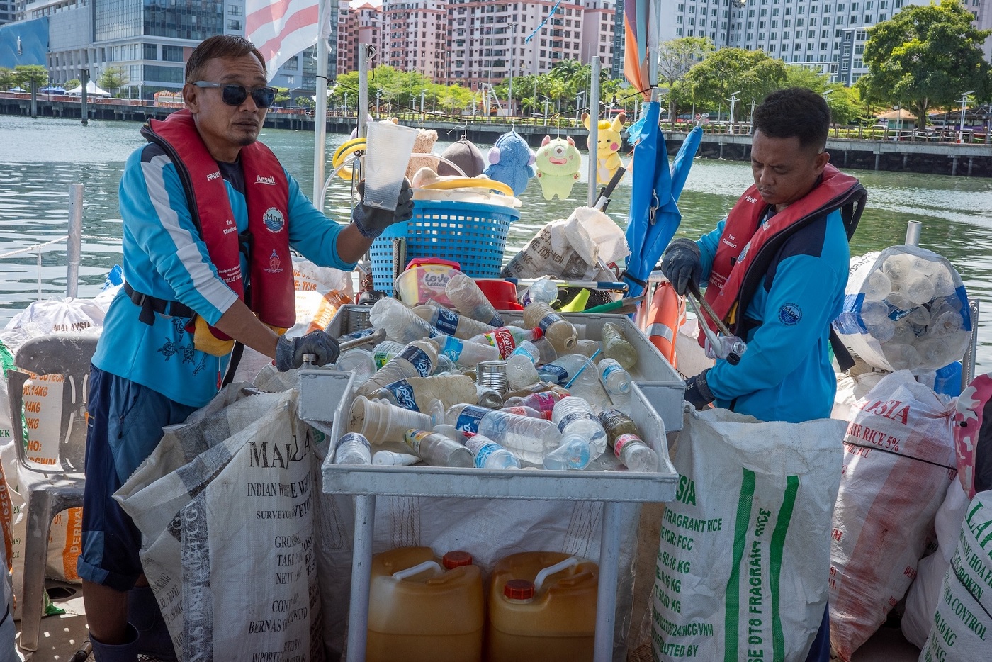 MRF crew members sorting through collected marine debris on the deck of the Mobula. The bottles and packaging are separated into repurposed rice sacks for transport to a local recycling centre.