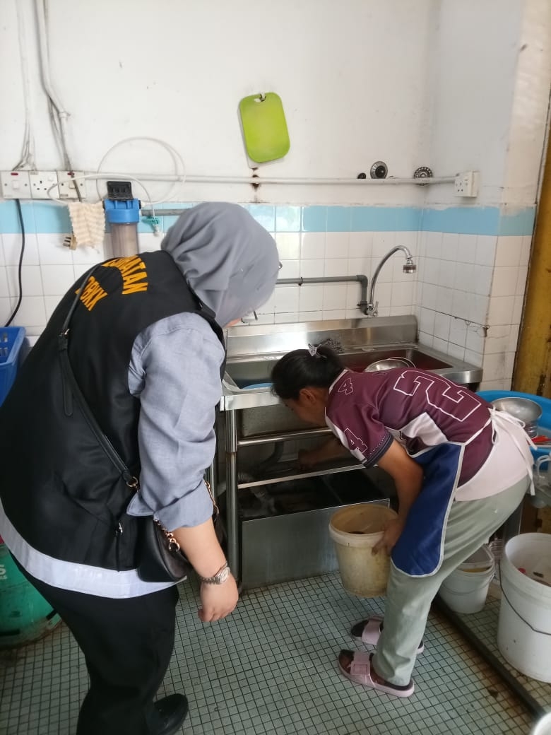An EHD personnel has a closer look at the grease-trap in this coffeeshop.